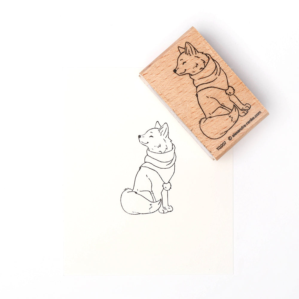 Ein Holzstempel von Alexandra Renke mit einem Hund im Halstuch, der sitzt und über seine Schulter schaut - ideal für Papierbastelprojekte.