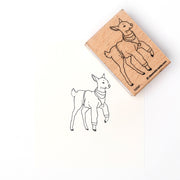 Eine Holzbriefmarke von Alexandra Renke zeigt den Druck einer stehenden Ziege mit Schal, entworfen von Reh Filine.