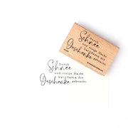 Ein Alexandra Renke Holzstempel mit deutschem Text und seinem Stempelgummi-Aufdruck auf weißem Papier, der den Weihnachtsmann und Geschenke erwähnt - ideal für festliche Papierprojekte.