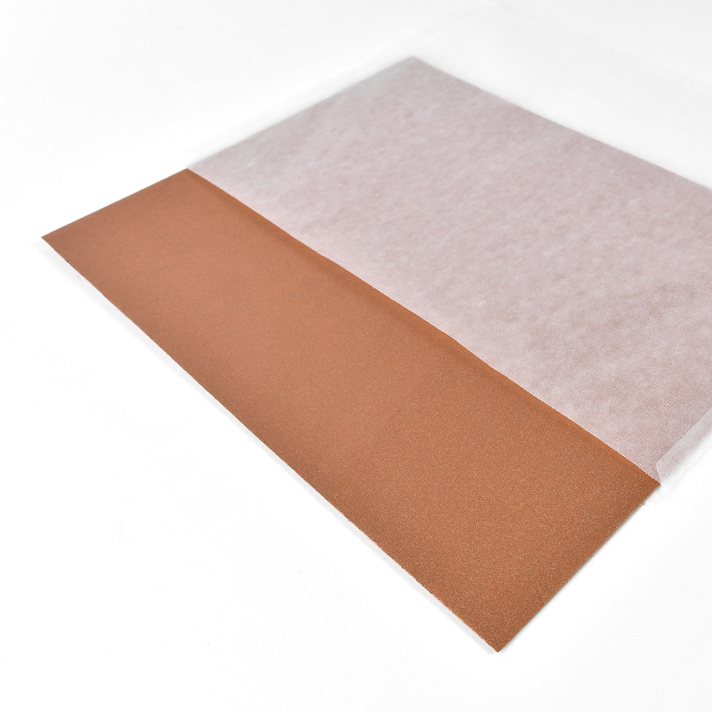 Ein Blatt braunes Sandpapier, teilweise bedeckt von einem eleganten, durchscheinenden weißen Blatt von Vivant Decorations BV, das an Geschenkpapier erinnert, auf weißem Hintergrund.
