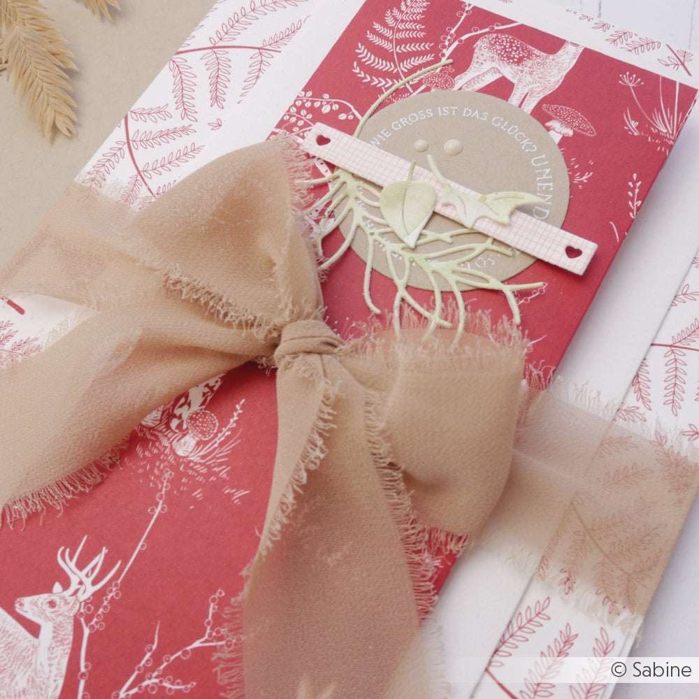 Geschenk von Vivant Decorations BV: beigefarbene Chiffonband-Schleife auf rotem, hirschähnlichem Geschenkpapier mit naturinspirierter Karte - ideal für Bastelprojekte oder kreative Deko-Ideen.