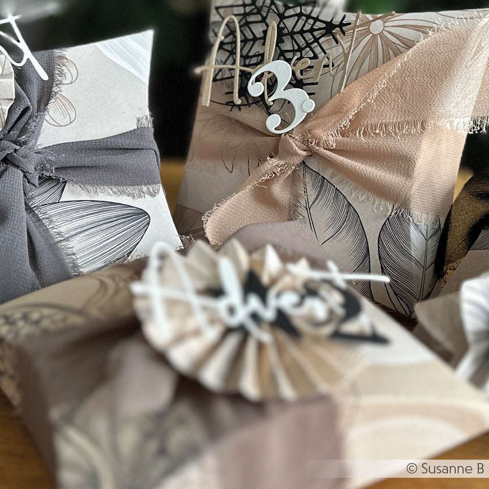 Drei Geschenkboxen von Vivant Decorations BV, verpackt in neutralem gemustertem Papier mit Stoffbändern, Anhängern und einem weichen Chiffonband - die perfekte Inspiration für Bastelprojekte oder kreative Dekoideen.