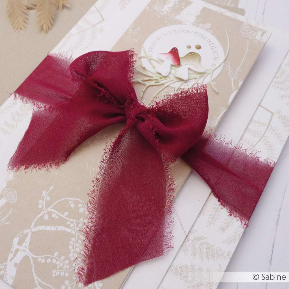 Eine beigefarbene Vivant Decorations BV-Karte mit einer roten Chiffonband-Schleife und zwei Vögeln, ideal für Bastelprojekte oder Deko-Ideen, abgebildet auf weißen Umschlägen.