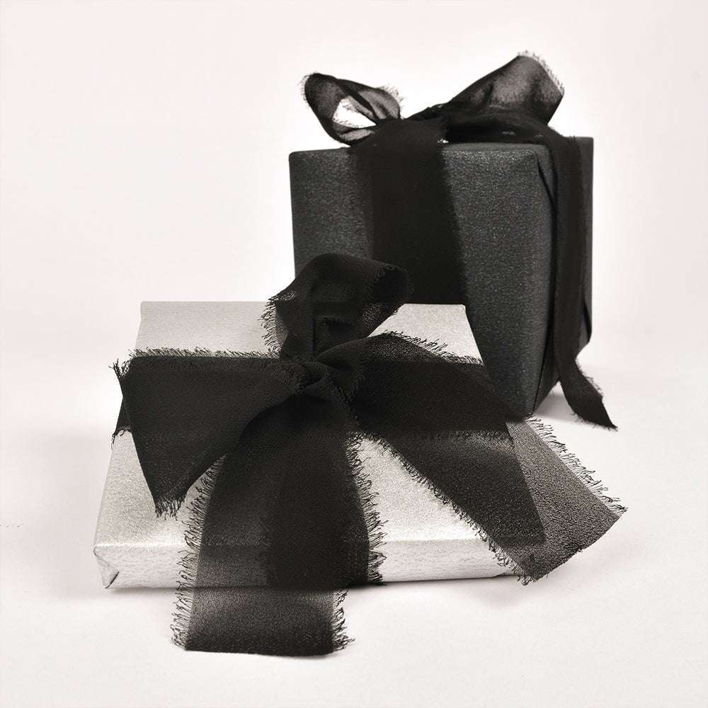 Zwei Geschenkboxen von Vivant Decorations BV - eine silberne, eine schwarze - jeweils mit einer großen schwarzen Chiffonband-Schleife versehen; perfekt für Deko Ideen oder kreative Bastelprojekte.