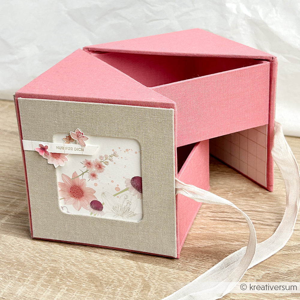 Die dreieckige Fotowürfelbox von Alexandra Renke in Rosa und Beige verfügt über zwei ausziehbare Schubladen, ein florales Design und eine weiße Schleife.