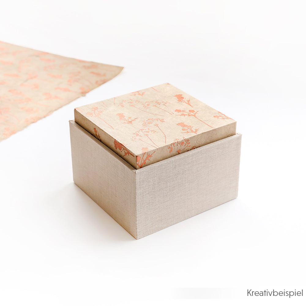 Quadratische beigefarbene Einsteckbox von Alexandra Renke mit einem floral gemusterten Deckel, leicht geöffnet auf weißer Oberfläche - ideal für stilvolle Geschenkverpackungen.