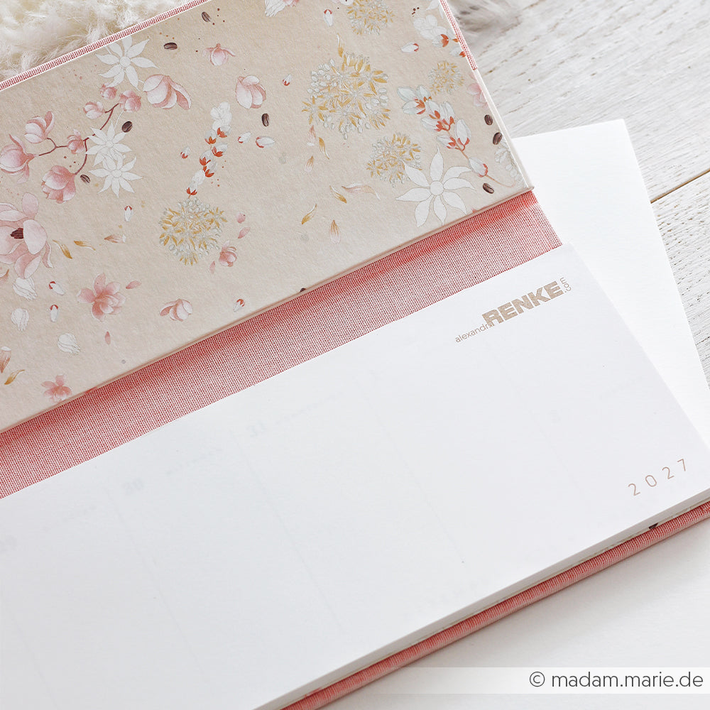 Offener Planer mit Blumenmuster und rosa Leinenbezug, mit einer Seite aus dem „Kalender 2027“ des PAPPKit-Bastelsets „Kalender“, dargestellt auf einem weißen Hintergrund.