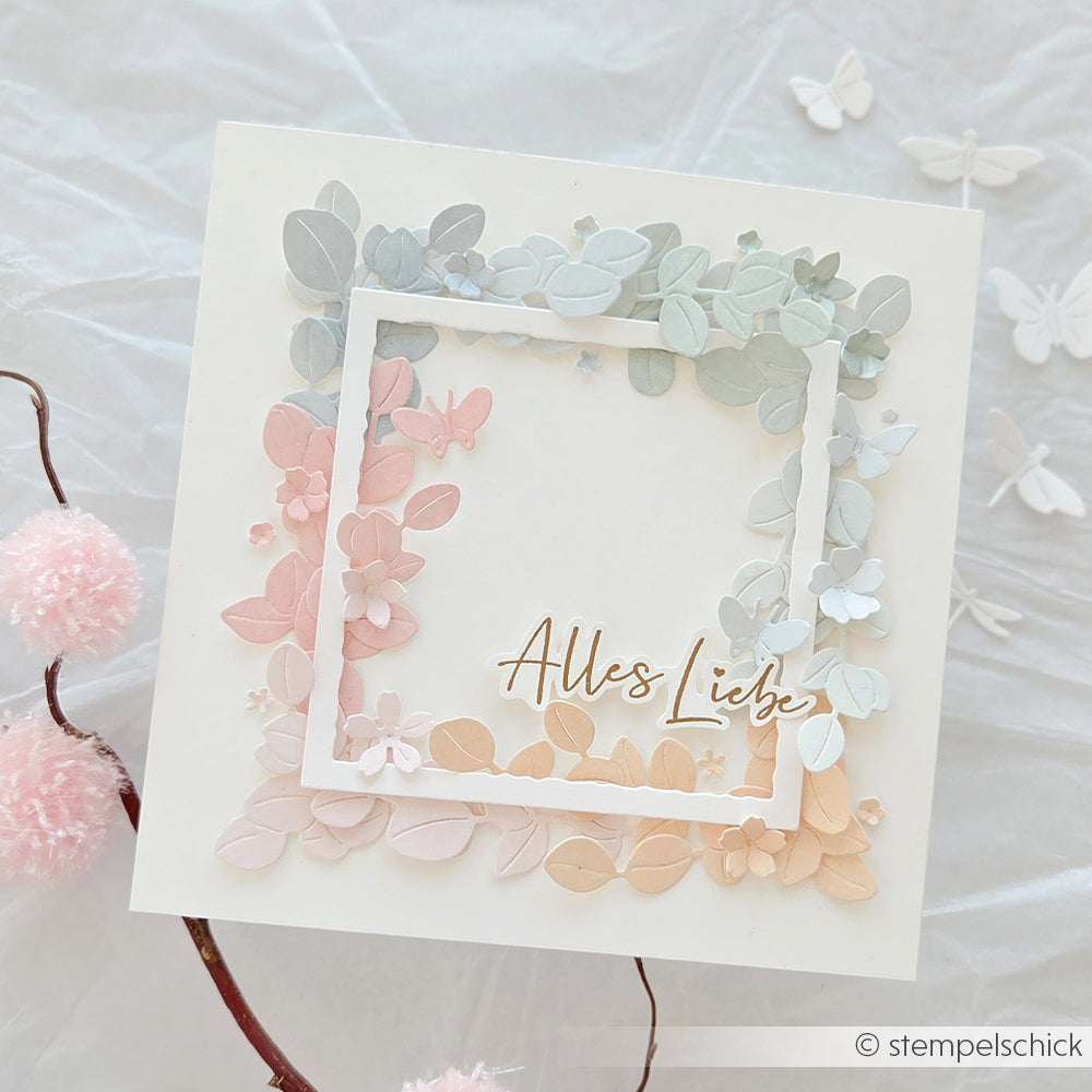 Quadratische Karte mit pastellfarbenen 3D-Blumenverzierungen, hergestellt mit Alexandra Renke DieCut Systeme und Stanzen für Designpapier, mit dem Text "Alles Liebe" in einem weißen Rahmen auf der Vorderseite.
