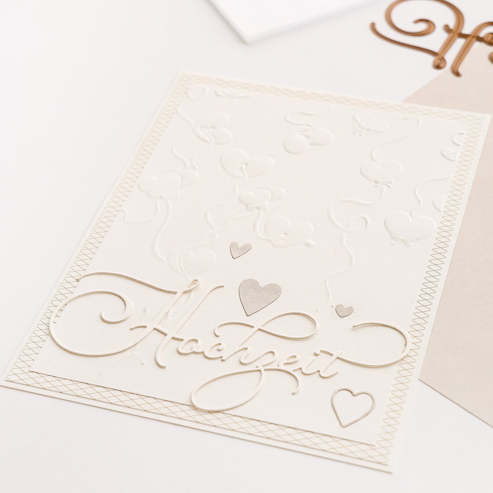 Weiße Hochzeitskarte von Alexandra Renke aus edlen Designpapieren mit geprägten Herzen und dem Schriftzug "Hochzeit" in eleganter Schrift - wunderschön veredelt mit der Motivstanze Hochzeit für einen zeitlosen Touch.