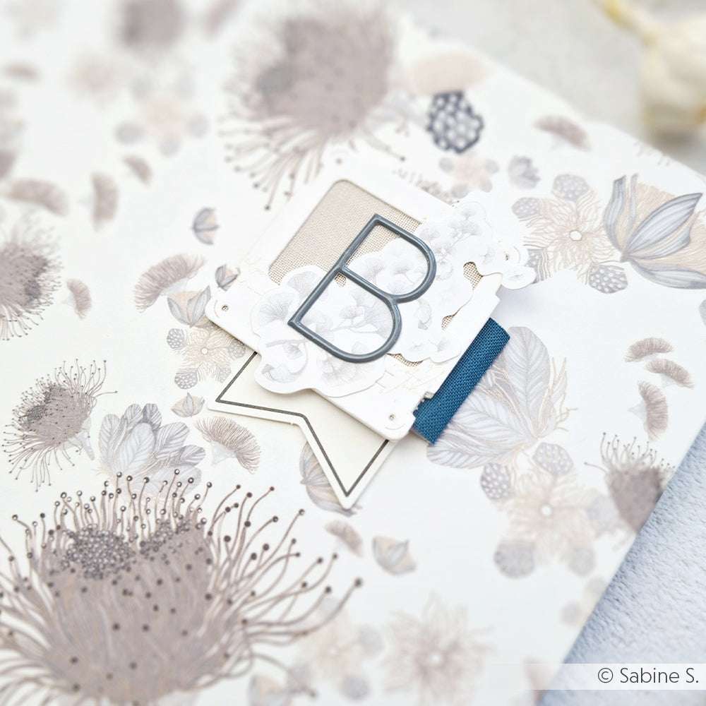 Eine floral gemusterte Karte von Alexandra Renke mit einem Diamantgrau-Buchstaben B und blauem Band, ideal zum Gestalten mit einem Alpha-Sticker aus der Kollektion Großes Alphabet.