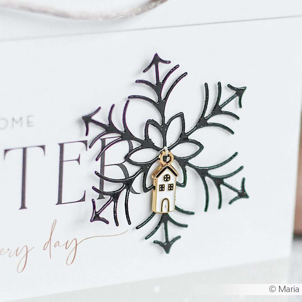 Alexandra Renke Schneeflocken-Anhänger aus Metall mit weißem Haus-Charme, elegant montiert auf einer weißen Karte mit Schreibschrift - ideal für Buchbindeprojekte oder festliche Geschenkdekoration.