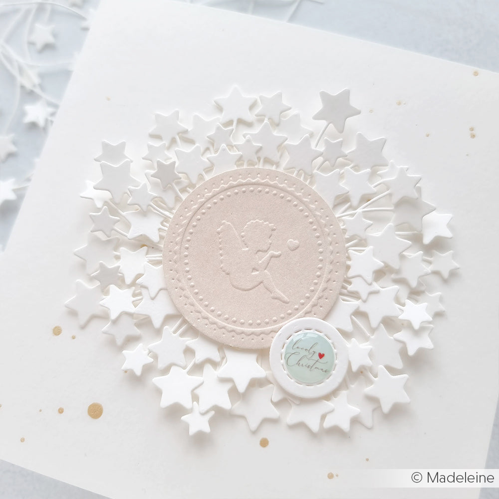 Mit dem Alexandra Renke Embossing Folder geprägte Karte mit einem Engel mit Herz in der Mitte, umgeben von weißen Sternen und einem kleinen runden "Love"-Anhänger.