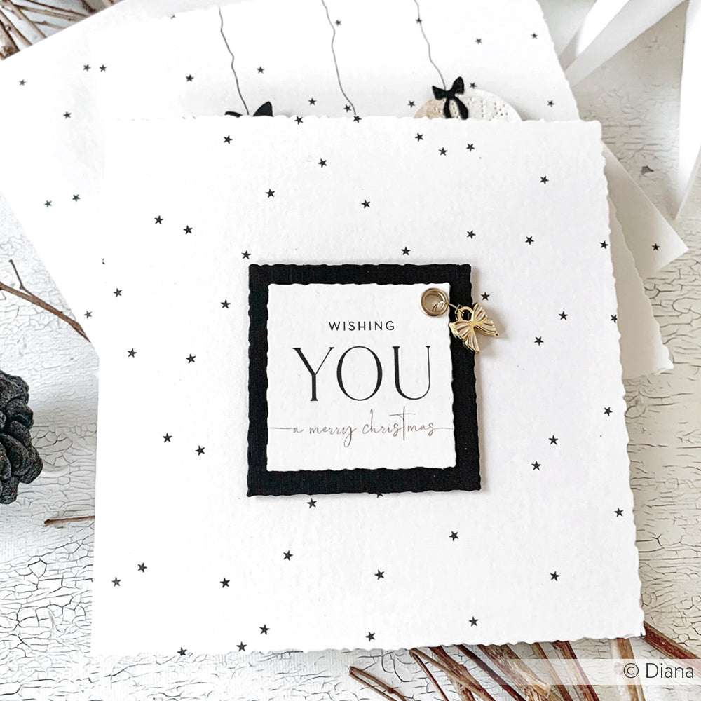 Eine handgefertigte Alexandra Renke Karte mit "Wishing you a merry Christmas" in einem quadratischen Rahmen, verziert mit einer Charm Schleife mit Streifen-ideal für Papierprojekte oder alle, die einzigartiges Buchbindezubehör lieben.