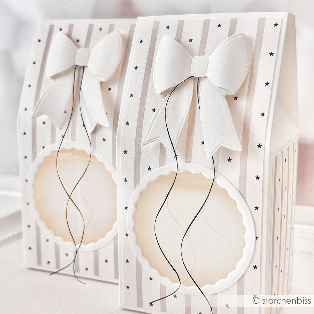 Zwei gestreifte Alexandra Renke Geschenkschachteln mit weißen Schleifen, Sternmustern und runden, transparenten Fenstern - perfekt, um die Schleifenpracht zu präsentieren oder Ihre Lieblingsmotive mit Cut & Emboss Folder in einer einzigartigen Verpackung auszustellen.