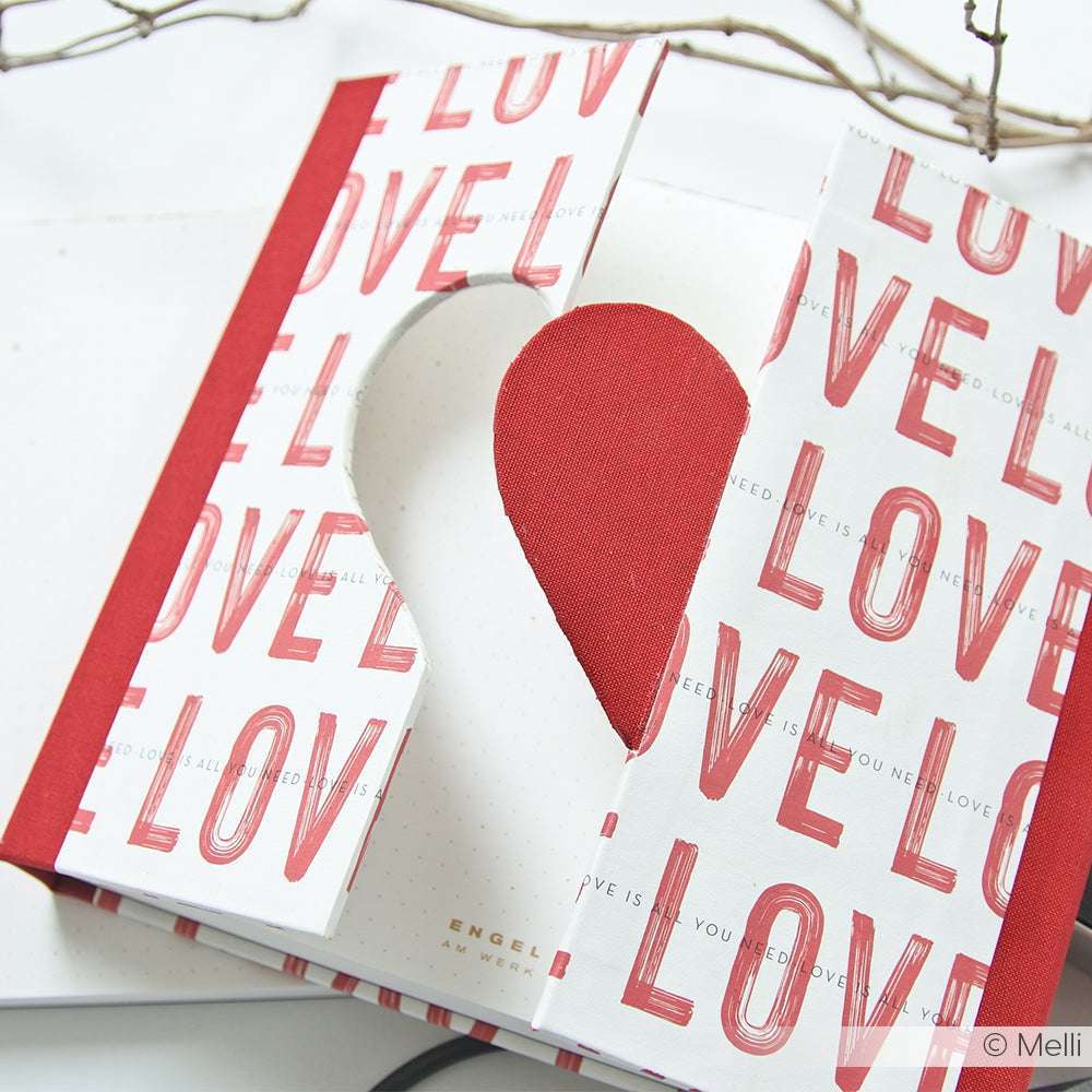 Ein Buch von Alexandra Renke mit "LOVE" auf dem Einband und einem herzförmigen Ausschnitt in der Mitte, der mit der PAPPcut Herz Technik hergestellt wurde und eine einzigartige Note hat.