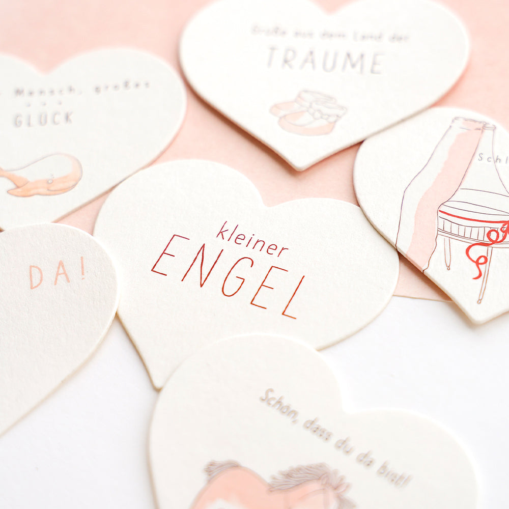 Ein Set weißer Herzen mit Schrift, hergestellt von Alexandra Renke mit präzisen Stahlbandstanzen und PAPPcuts®-Techniken.