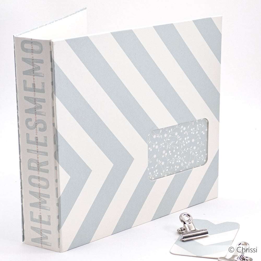 Hellblau-weißes Chevron-Album von Alexandra Renke mit dem Schriftzug "MEMORIES" auf dem Rücken, Buchbinden und einem dekorativen herzförmigen Clip.