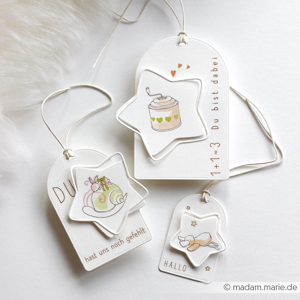 Drei weiße Geschenkanhänger von Alexandra Renke mit niedlichen Illustrationen, deutschem Text und Sternenverzierungen - ideal für Bastelprojekte oder zum einfachen Übertragen von Motiven mit Rub-On Transferfolie.