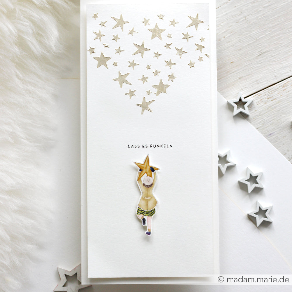 Eine weiße Karte von Alexandra Renke mit goldenen Sternen, einem Mädchen, das einen Stern hält, und "LASS ES FUNKELN" - perfekt für Schablone Papierprojekte oder um mit wiederverwendbaren Stencils zu zaubern.