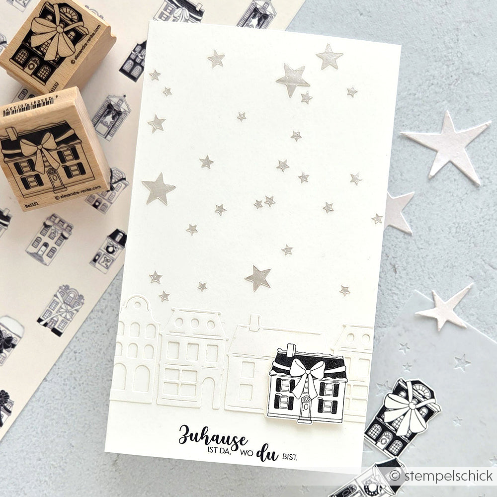 Weiße Karte mit gestempelten Häusern, silbernen Sternen, die mit der Schablone Sternenhimmel von Alexandra Renke hergestellt wurden, und dem deutschen Spruch "Zuhause ist da, wo du bist" - die perfekte Inspiration für Ihre Schablonen Papierprojekte.