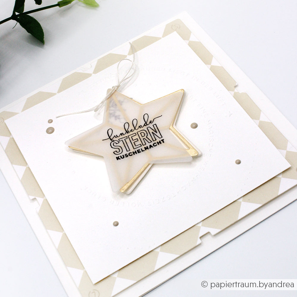 Quadratische Karte von Alexandra Renke mit sternförmigem Ornament und deutschem Text, hergestellt mit Buchbindentechnik und PAPPcuts auf einem geometrischen Hintergrund in Beige und Weiß.