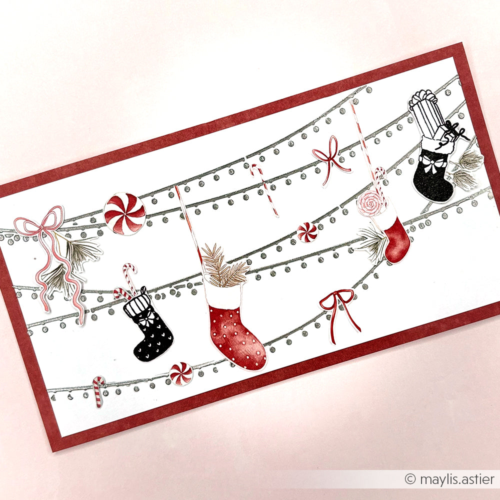 Festliche Karte mit Strümpfen, Zuckerstangen, Schleifen und Süßigkeiten auf Girlanden mit rotem Rand - ideal für Schablonen-Papierprojekte oder mit wiederverwendbaren Schablonen von Alexandra Renke für fröhliche Gestaltungen.