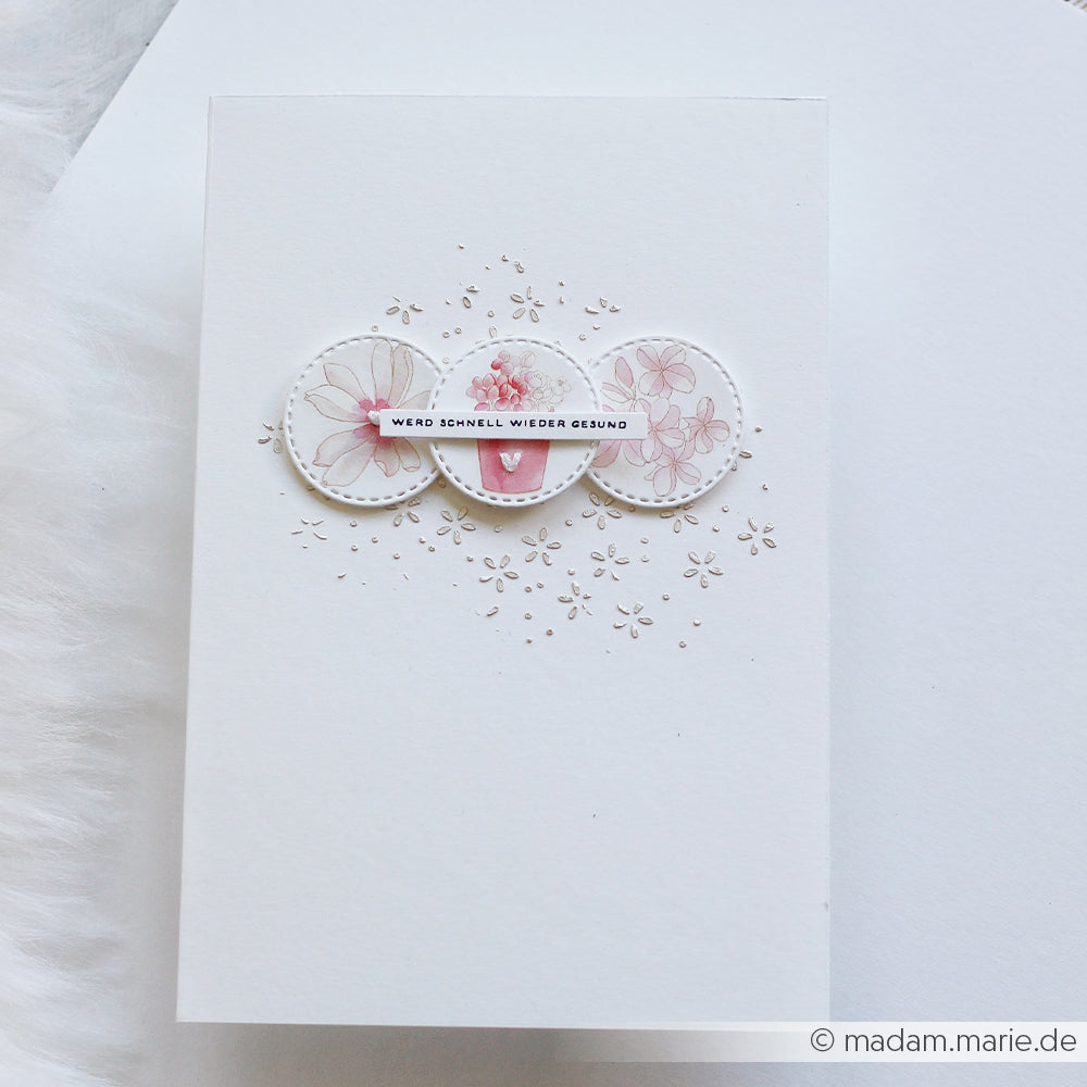 Weiße Karte von Alexandra Renke mit drei rosafarbenen Blumenkreisen, die mit Rub-On-Transferfolien erstellt wurden, und dem deutschen Text "Werd schnell wieder gesund" - ideal für Bastelprojekte oder Rosarote Blütenpoesie.
