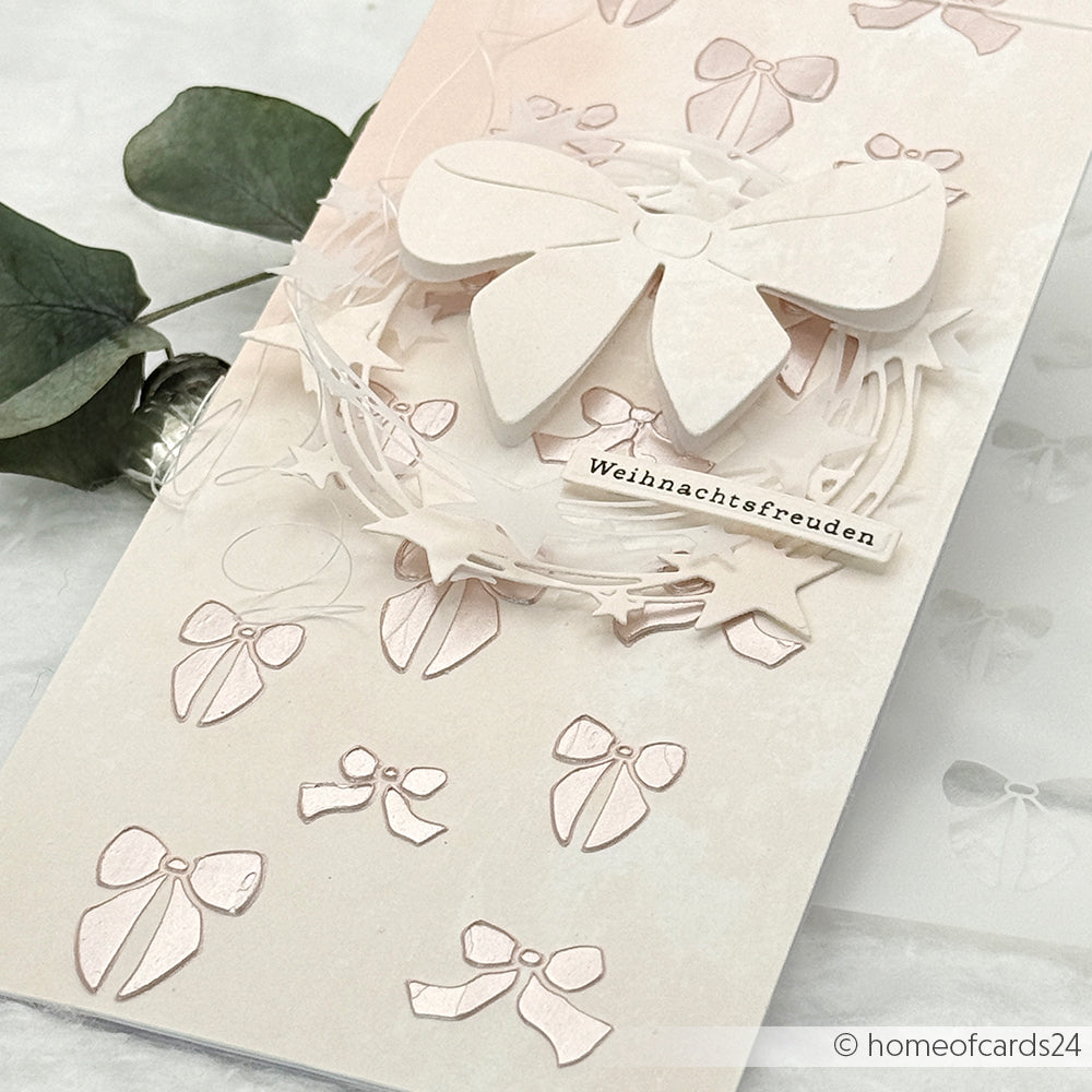Handgefertigte Karte von Alexandra Renke mit einer erhabenen weißen Schleife, geprägten Schleifen mit wiederverwendbaren Schleifenregen-Schablonen und "Weihnachtsfreuden" auf der Vorderseite für ein einzigartiges festliches Design.
