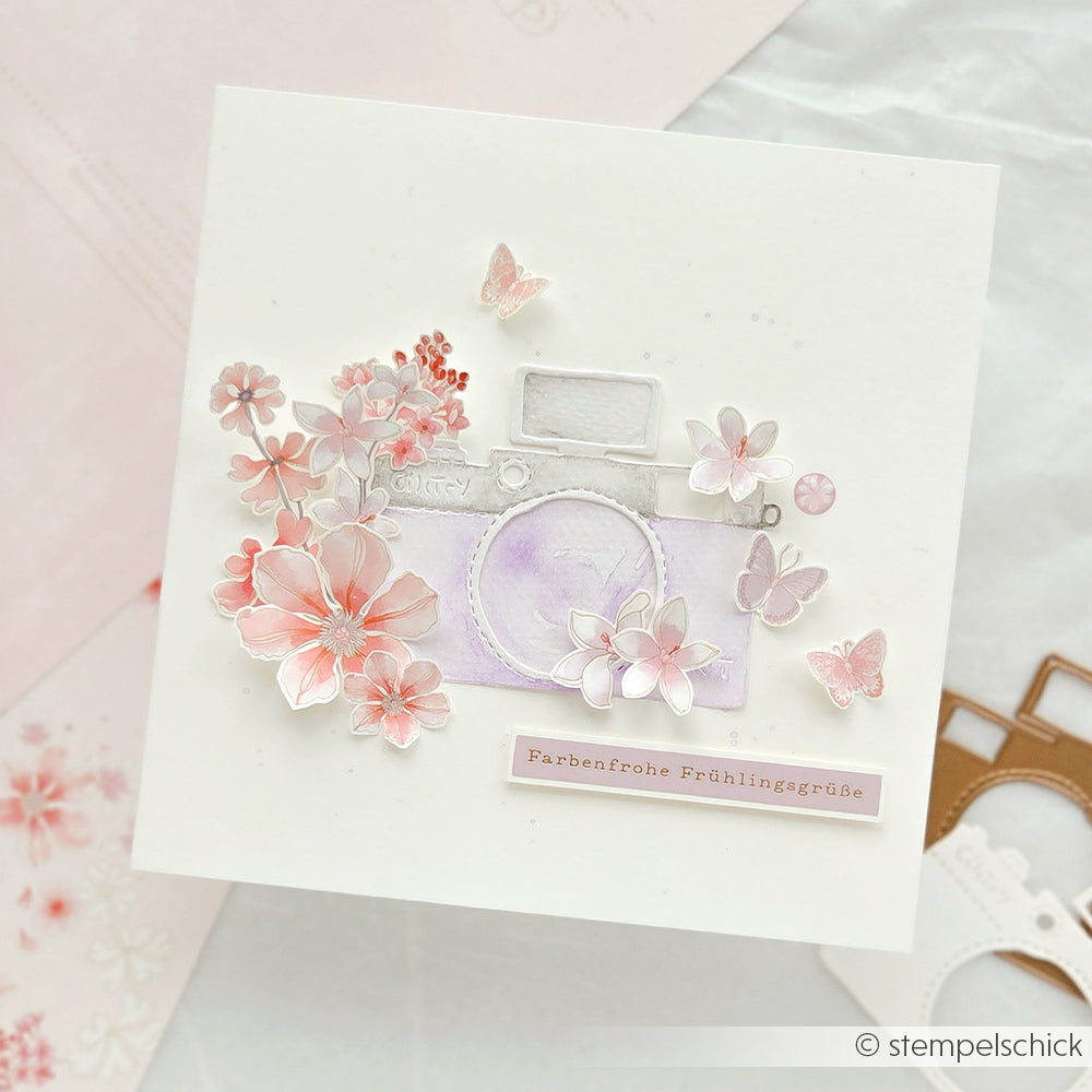 Handgemachte Karte von Alexandra Renke mit einer pastellfarbenen Kamera, rosa Blumen, Schmetterlingen und floralen Motiven plus deutschem Gruß - ideal für Bastelprojekte oder zum Personalisieren mit Rub-On Transferfolien.