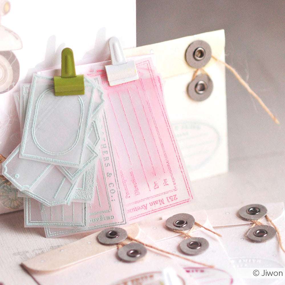 Verschiedene pastellfarbene Papeterie-Anhänger und Karten mit Klammern, umgeben von Umschlägen mit Kordelzug von Alexandra Renke - ideal für Ihre Projekte mit Acrylblock und Photopolymer-Stempeln oder Clear Stamps.