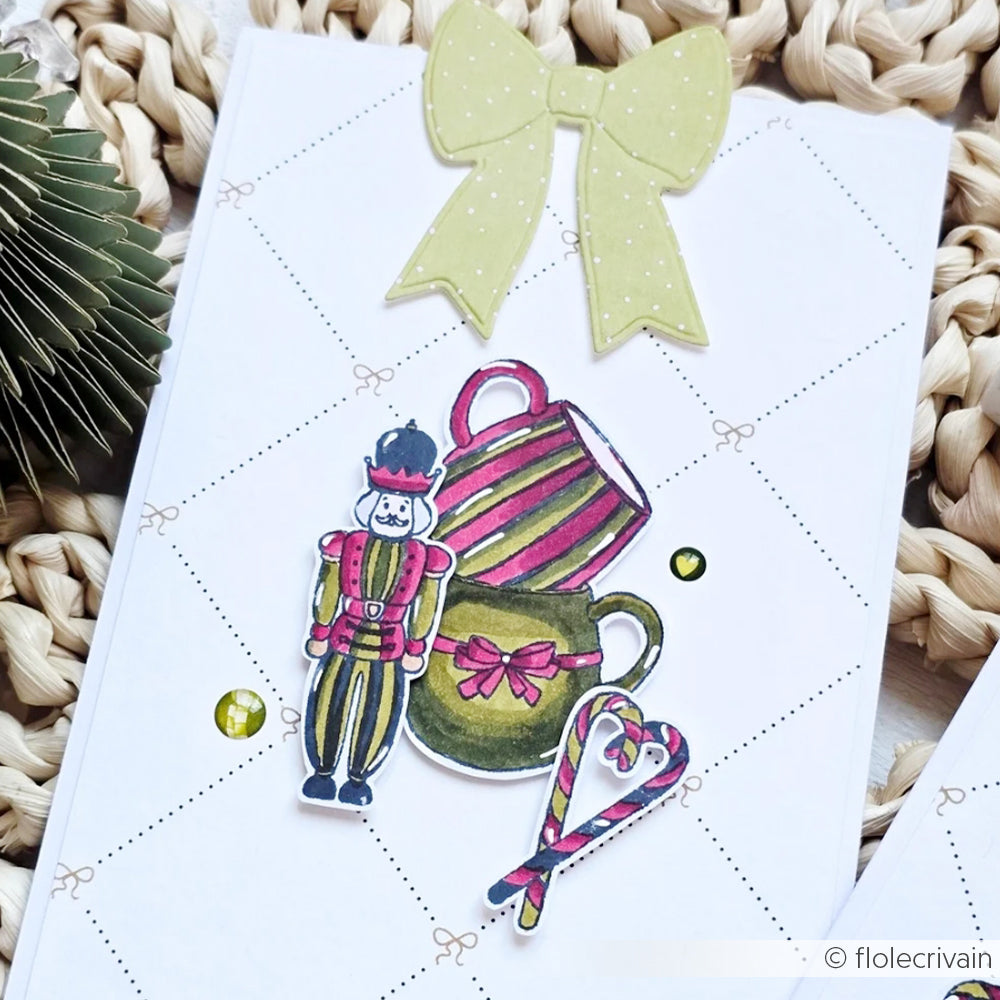 Handgemachte Karte von Alexandra Renke mit gelber Schleife, gestapelten Tassen, Nussknackerfigur und Zuckerstangenmotiven, die mit hochwertigen Photopolymerstempeln erstellt wurden.