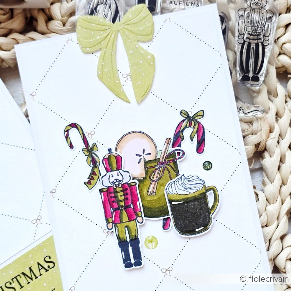 Handgefertigte Weihnachtskarte von Alexandra Renke mit einem Nussknacker, Zuckerstangen, Tassen und einer grünen Schleife auf gemustertem weißem Hintergrund, gestaltet mit einem festlichen Clear Stamp für klare, charmante Details.