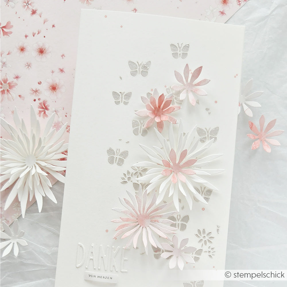 Weiß-rosa 3D-Dankeskarte mit Blumenmotiv und Schmetterlingsakzenten auf einem hellen, gemusterten Hintergrund, gestaltet mit wiederverwendbaren Schablonen von Alexandra Renke wie der Schablone „Florale Schmetterlinge“ – ideal, um Ihren Papierprojekten einen Hauch von Eleganz zu verleihen.