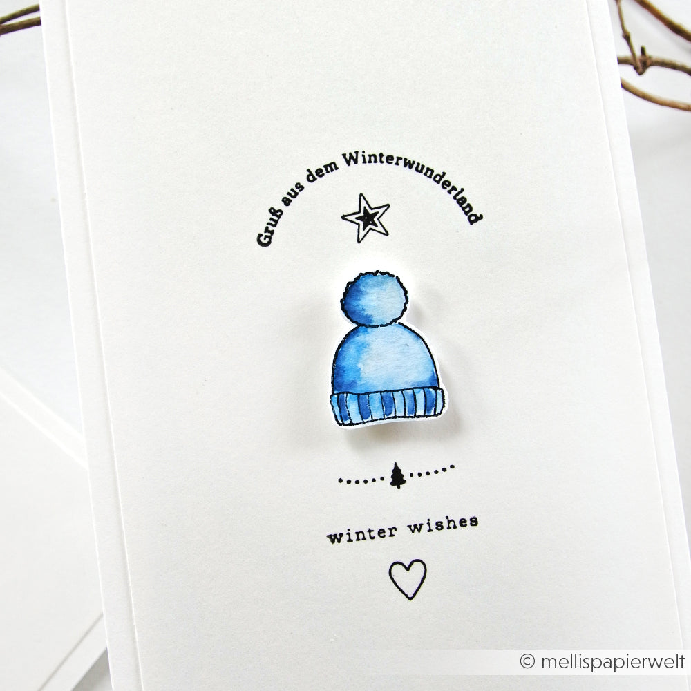 Minimalistische Karte von Alexandra Renke mit blauer Wintermütze, deutschem Gruß, Winterwünschen, einfachen Stern- und Herzzeichnungen - ideal für die Kuschelzeit. Hergestellt mit hochwertigen Photopolymer-Klarsichtstempeln für gestochen scharfe Details.