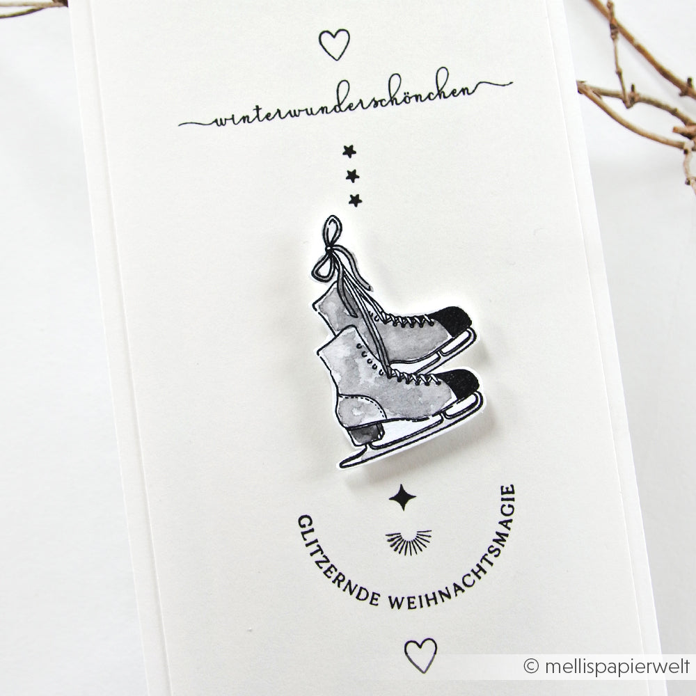Eine Karte mit einer Zeichnung von Schlittschuhen, die mit einem Alexandra Renke Clear Stamp und dem deutschen Spruch "Glitzernde Weihnachtsmagie" gemacht wurde - perfekt für die Kuschelzeit.