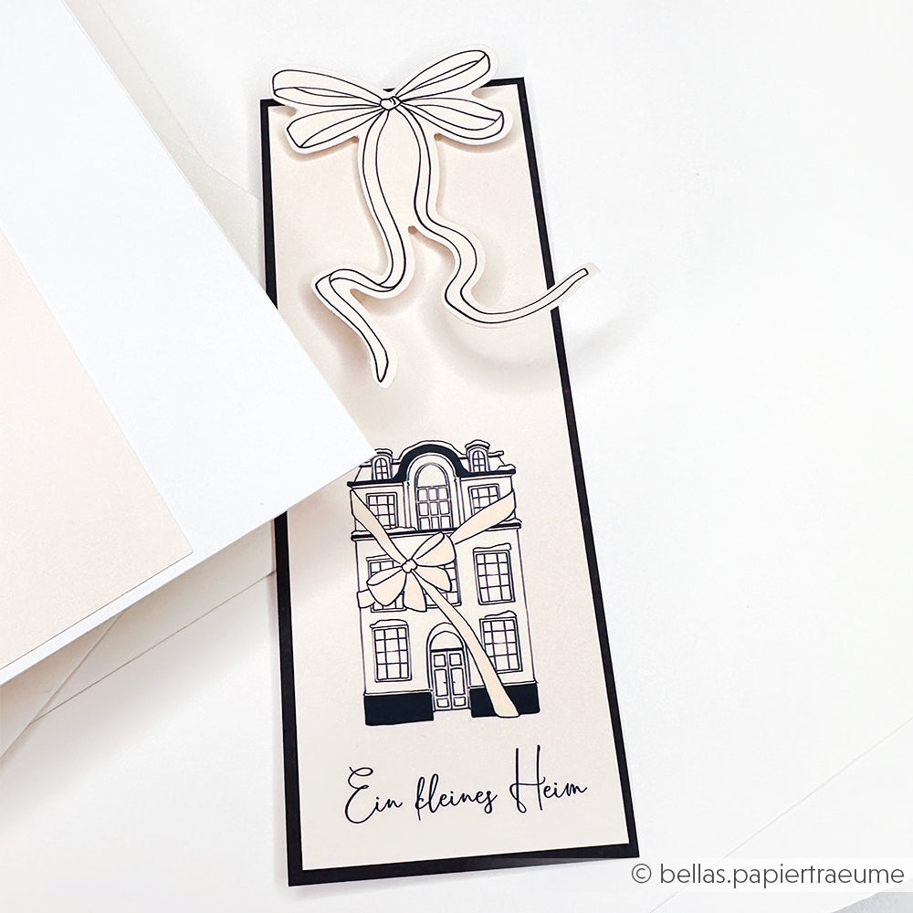Eine Karte von Alexandra Renke zeigt ein illustriertes Gebäude, eine große Schleife und den deutschen Text "Ein kleines Heim" - perfekt für Papierprojekte und Fans von Photopolymerstempeln oder Klarsichtstempeln.