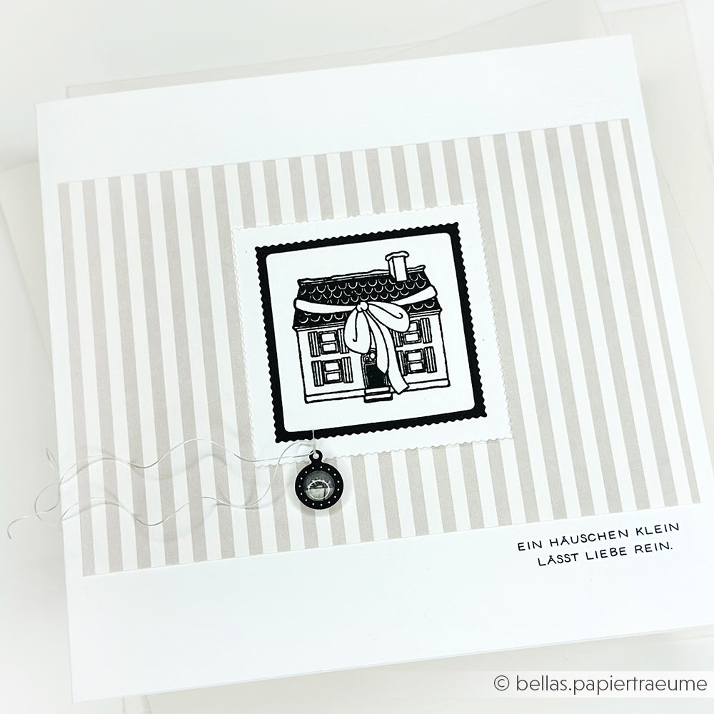 Quadratische Karte von Alexandra Renke mit einer schwarz-weißen Hausillustration, gestreiftem Hintergrund und einem kleinen Uhrenanhänger. Der deutsche Text darunter eignet sich perfekt, um Ihre Lieblingsmotive mit Photopolymer Stempel hervorzuheben.