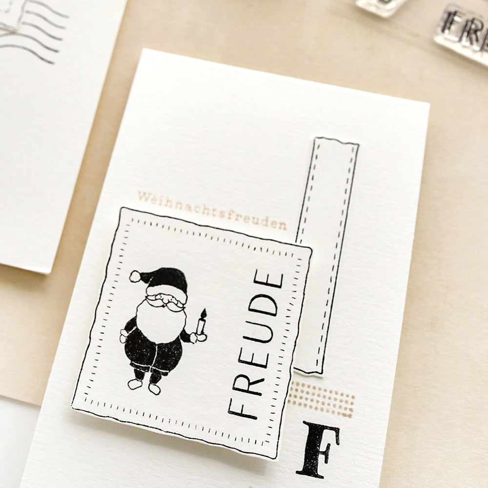 Eine weiße Karte von Alexandra Renke mit einer Weihnachtsmann-Illustration zeigt "FREUDE" und "Weihnachtsfreuden", gestaltet mit einem Photopolymer-Stempel für knackige Kompositionsformen-Stiche.