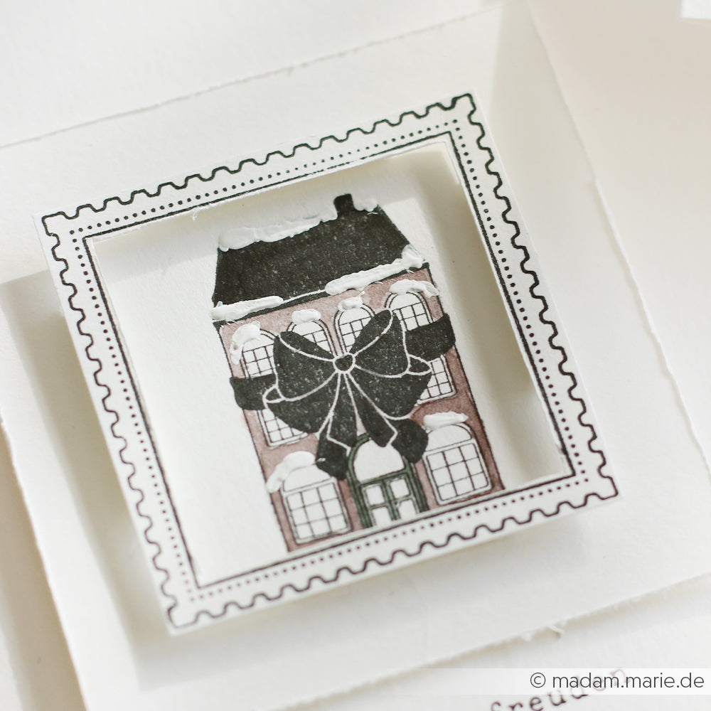 Illustration eines Hauses mit einer großen schwarzen Schleife, gerahmt wie eine Briefmarke auf weißem Papier, entworfen von Alexandra Renke.