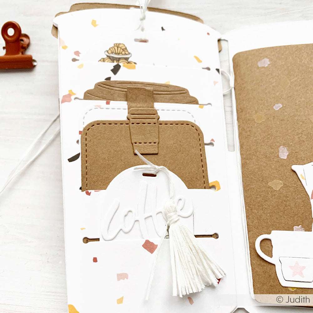 Braunes und weißes Bastelpapier mit einem Koffer, Kaffeetext, einer weißen Quaste und kreativen Akzenten, hergestellt mit Alexandra Renke Kaffee To Go Dies auf einer dekorierten Seite.