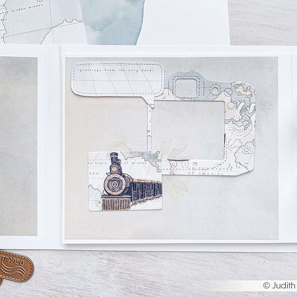 Die Papierschnitte von Alexandra Renke zeigen einen alten Zug, eine Sprechblase und ein Kameramotiv auf einem Kartenhintergrund - perfekte Akzente für Scrapbook-Layouts, die mit DieCut Systemen erstellt wurden.