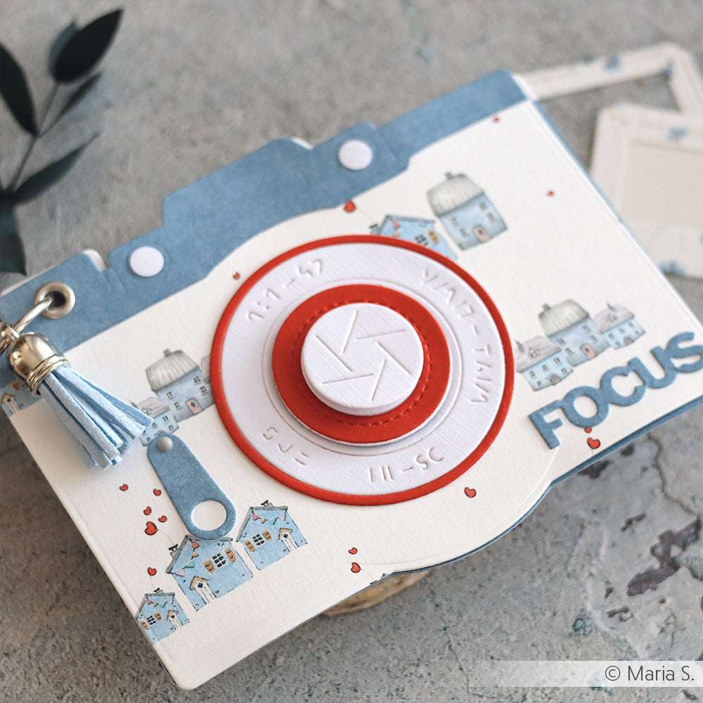 Eine handgefertigte Karte in Form einer Kamera von Alexandra Renke, hergestellt mit der Motivstanze Kamera Objektiv und verziert mit bunten Designpapieren mit Häusern und dem Wort "FOCUS".