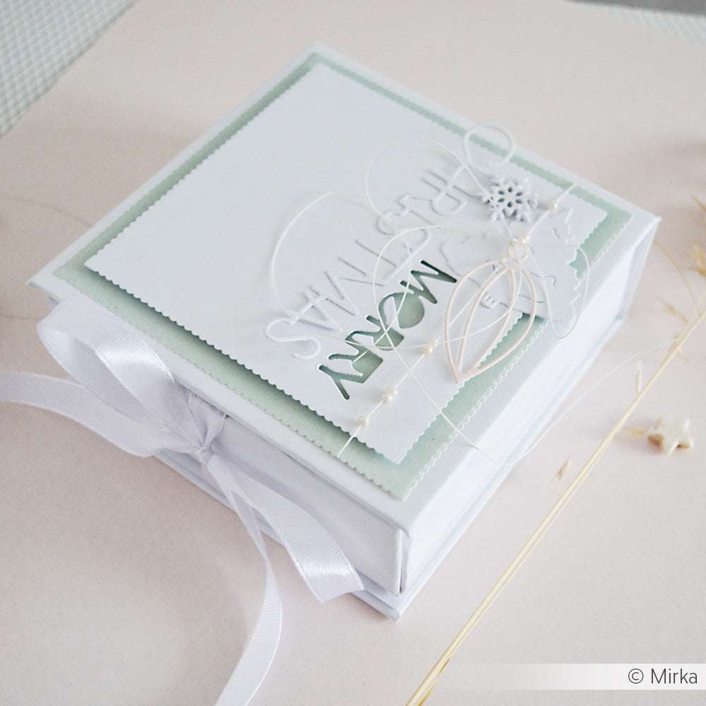 Quadratische weiße Geschenkschachtel von Alexandra Renke, verziert mit "Merry Christmas" auf dem Deckel, Schleife, zarten Verzierungen und elegantem Briefmarkenrand von Stanze.