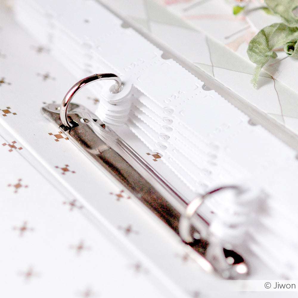 Nahaufnahme eines aufgeschlagenen Alexandra Renke Metall-Ringbuchs mit weißen Trennblättern, perfekt für die Organisation von DieCut Systemen und Stanzen auf einer gemusterten Oberfläche.