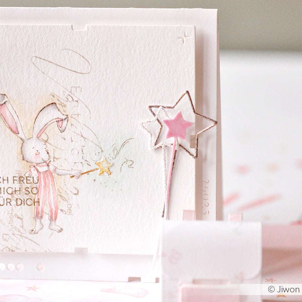 Ein handgezeichnetes Häschen hält einen Zauberstab zwischen zart pastellfarbenen und rosafarbenen Sternenstäben - ideal für Alexandra Renke Designpapiere oder zum Basteln mit Motivstanze 3 Zauberstäbe.
