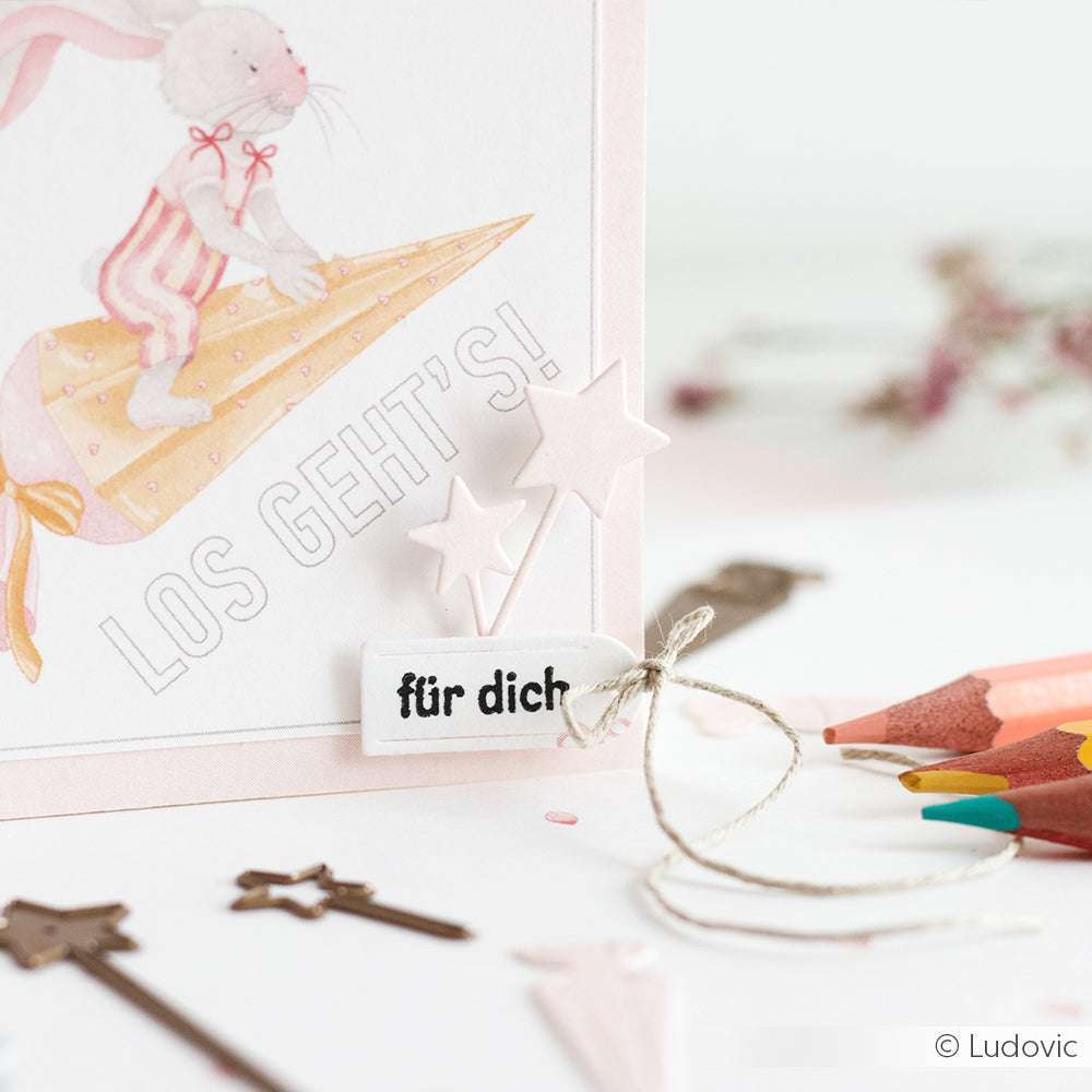 Grußkarte von Alexandra Renke mit einem Hasen auf einem Bleistift, dem Text LOS GEHTS! und einem "für dich"-Anhänger mit Sternen - ideal für die Verwendung mit Ihren bevorzugten DieCut Systemen.