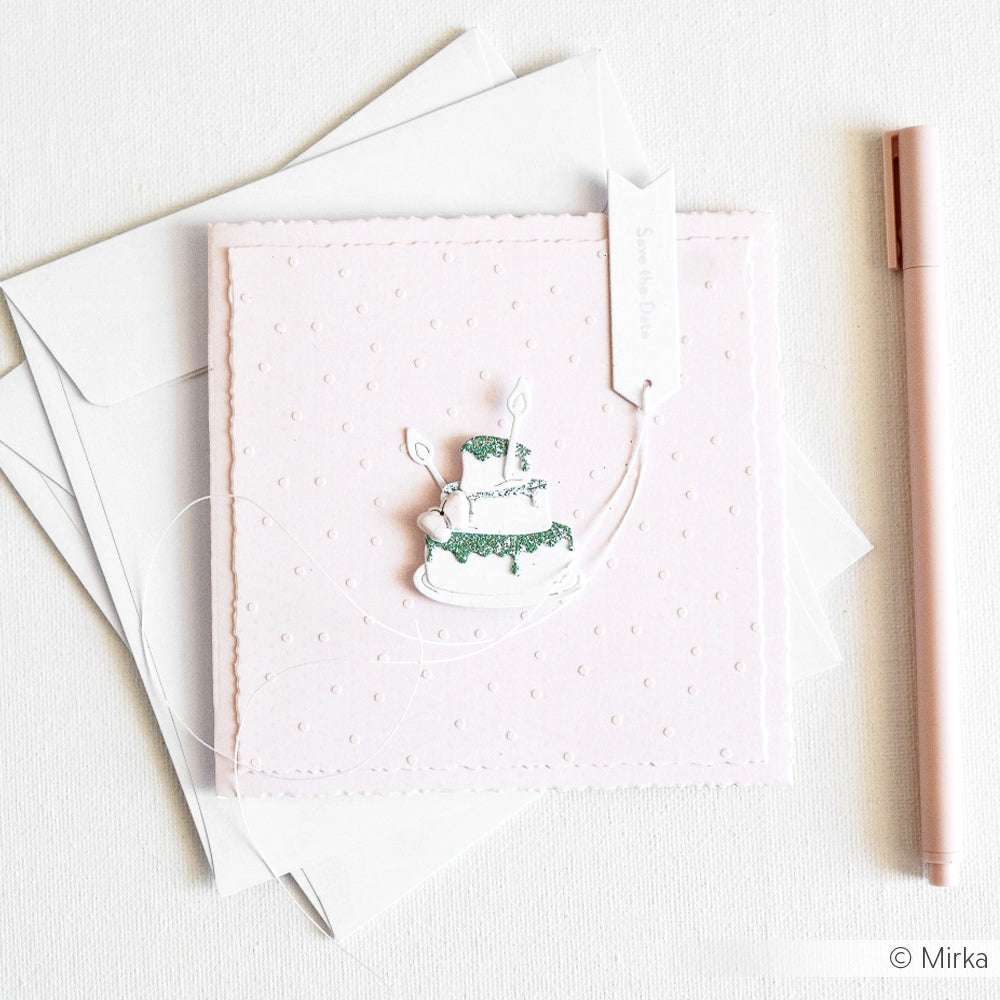 Quadratische rosafarbene Karte von Alexandra Renke mit einem Tortenmotiv aus der Motivstanze Torte mit Kerzen, mit Umschlägen und einem rosa Stift auf weißem Hintergrund.