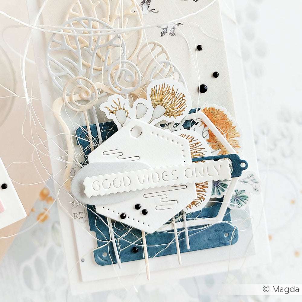 Handgemachte Karte von Alexandra Renke mit geschichteten Papierausschnitten, getrockneten Blumen und einem mit Motivstanze Etikett Vic 2 hergestellten Anhänger mit der Aufschrift "GOOD VIBES ONLY" in weißen Buchstaben.