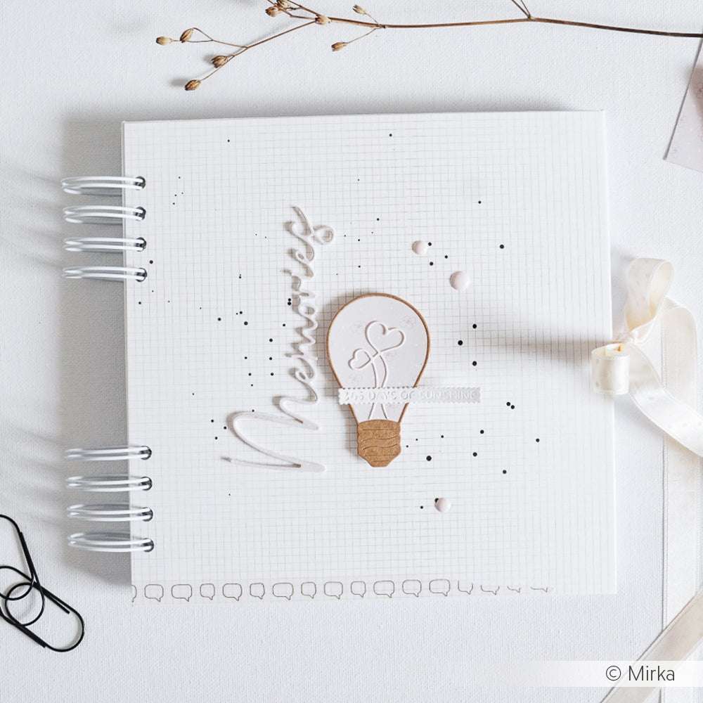 Ein weißes Scrapbook von Alexandra Renke mit dem Motiv "Memories" und einem Heißluftballon auf dem Umschlag, der mit kleinen Punkten verziert ist - hergestellt mit Stahlstempeln für präzise Details.