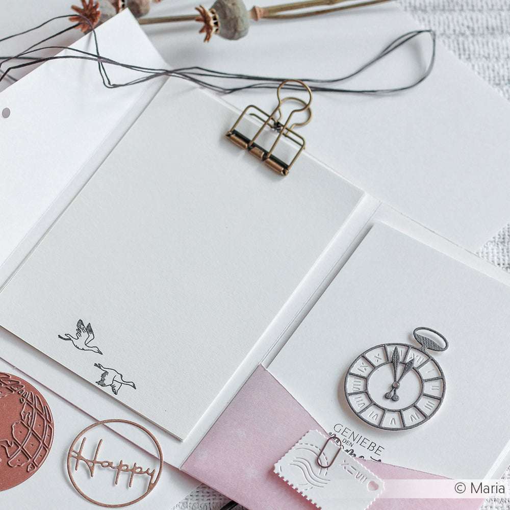 Eine Blanko-Notizkarte von Alexandra Renke mit fliegendem Vogelmotiv, Büroklammern und einer Motivstanze Taschenuhr liegt elegant auf dem Schreibtisch - ideal für kreative Projekte mit DieCut Systemen und Designpapieren.
